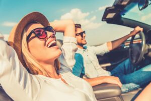Young man aand woman in a convertable car on a road trip