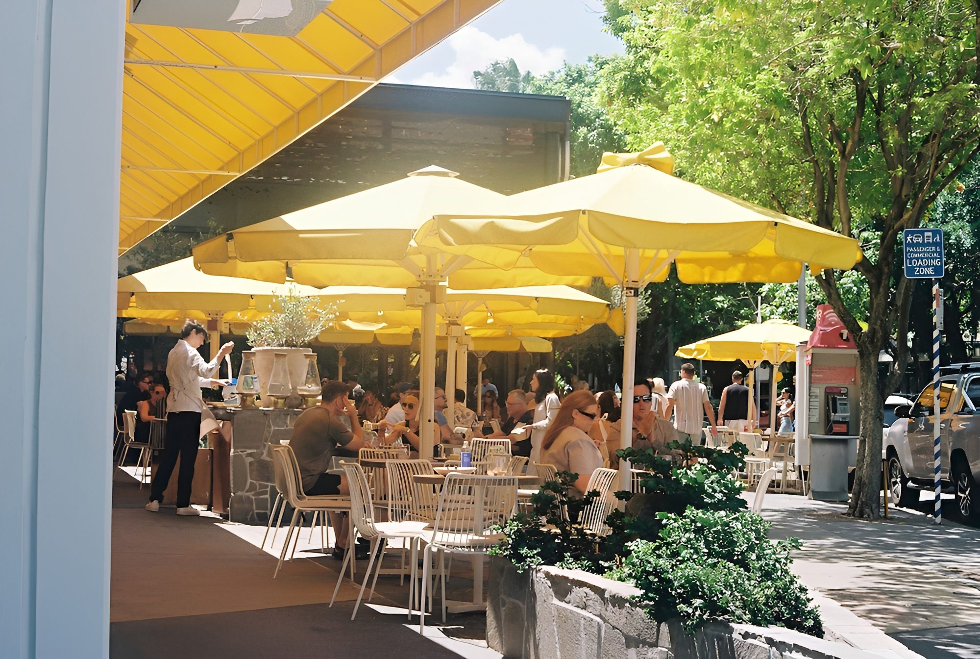 Outdoor cafe with yellow umbrellas and diners.