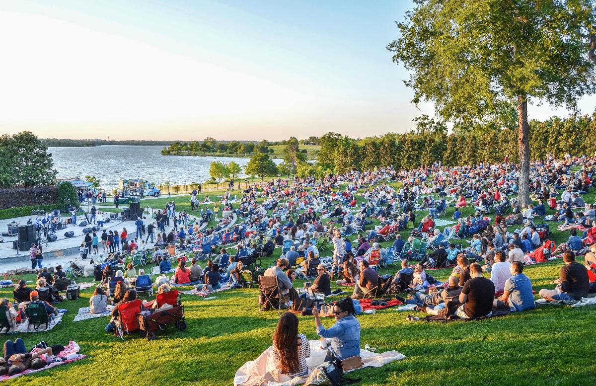Outdoor concert audience by a lakeside park.