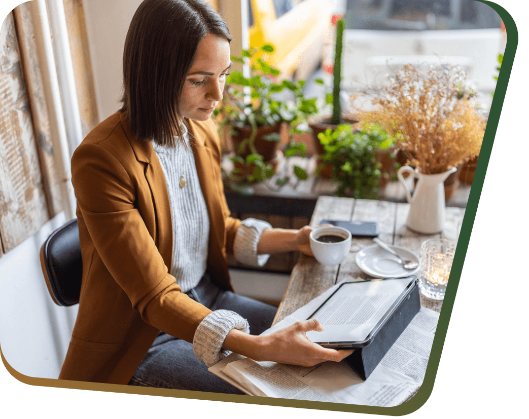 Woman in café reading tablet while holding coffee