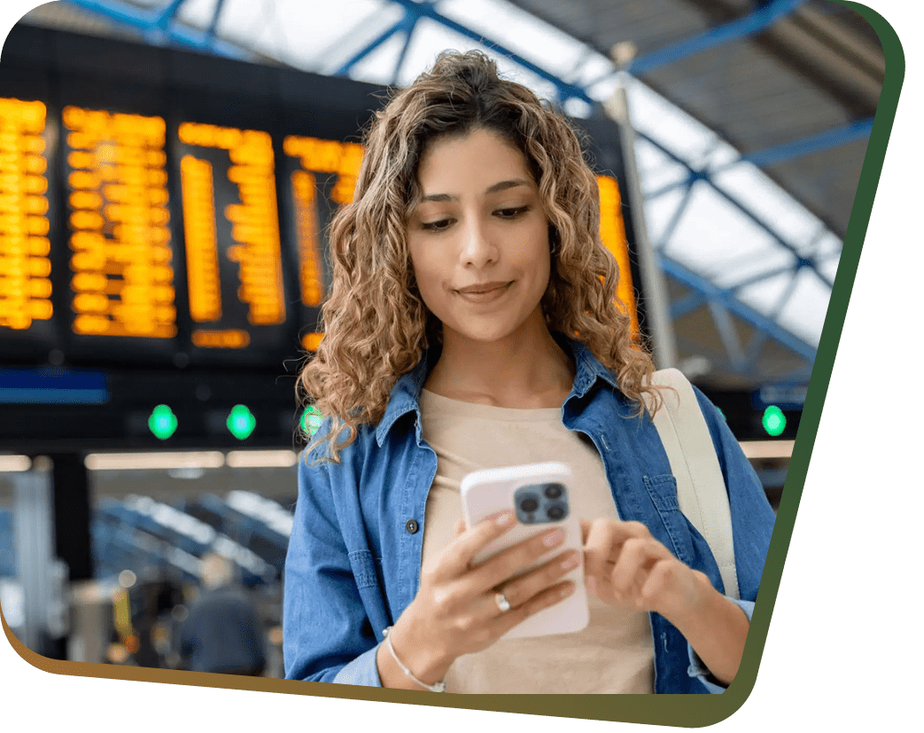 Woman checking phone under airport departure board
