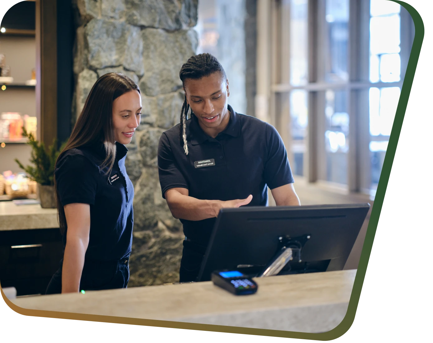 Employees discussing at front desk computer terminal.