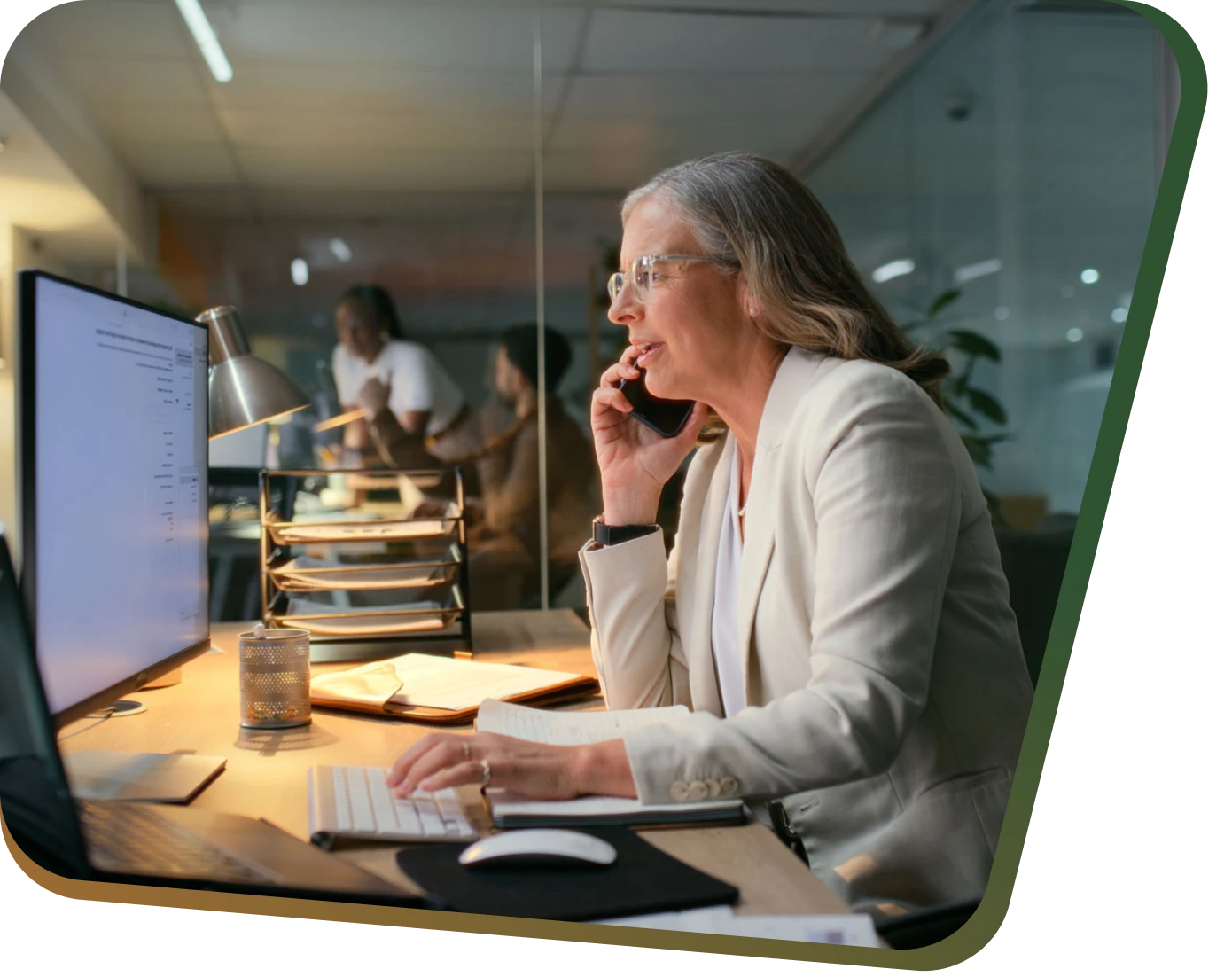 Woman working at desk, talking on phone.