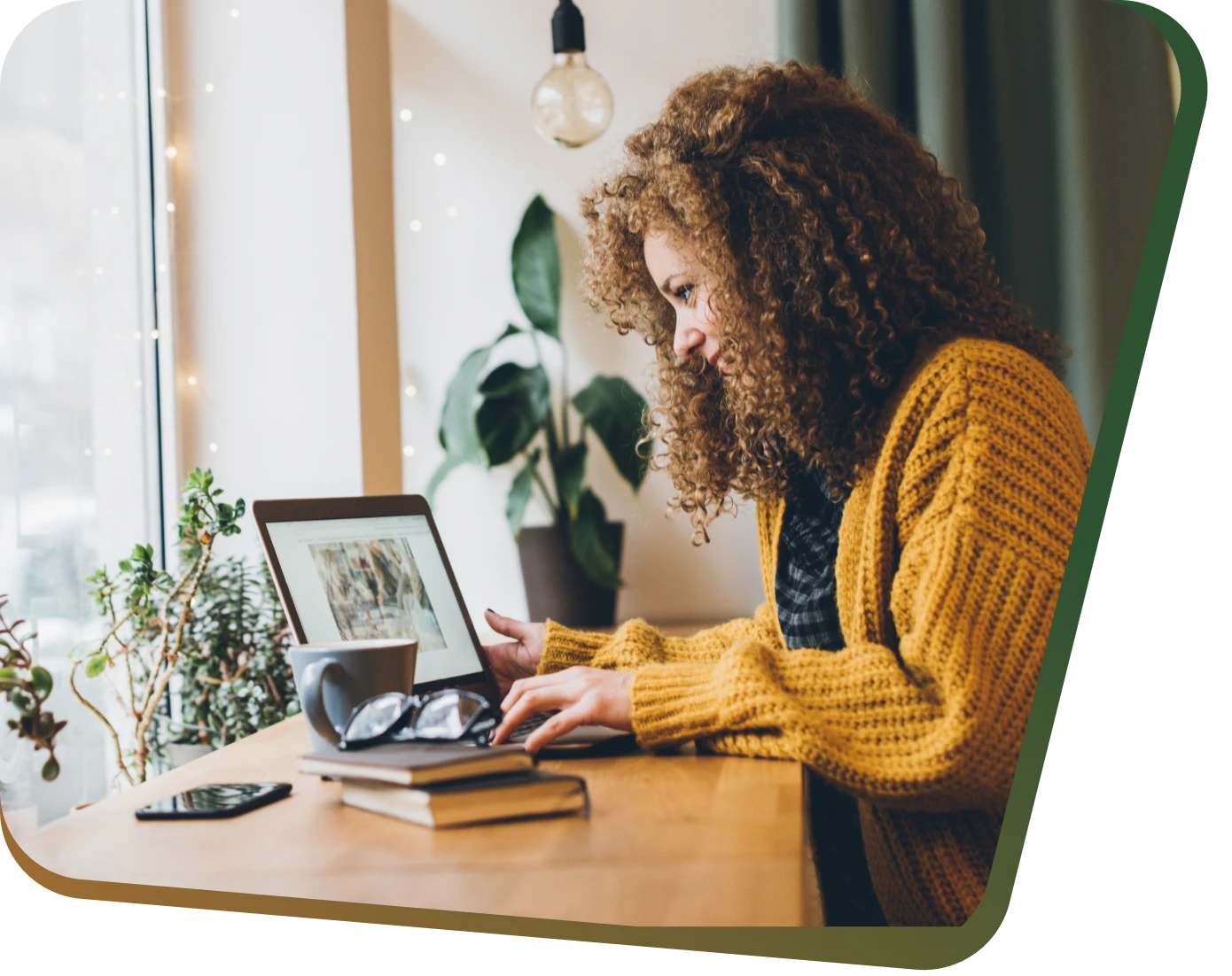 Woman working on laptop near window.