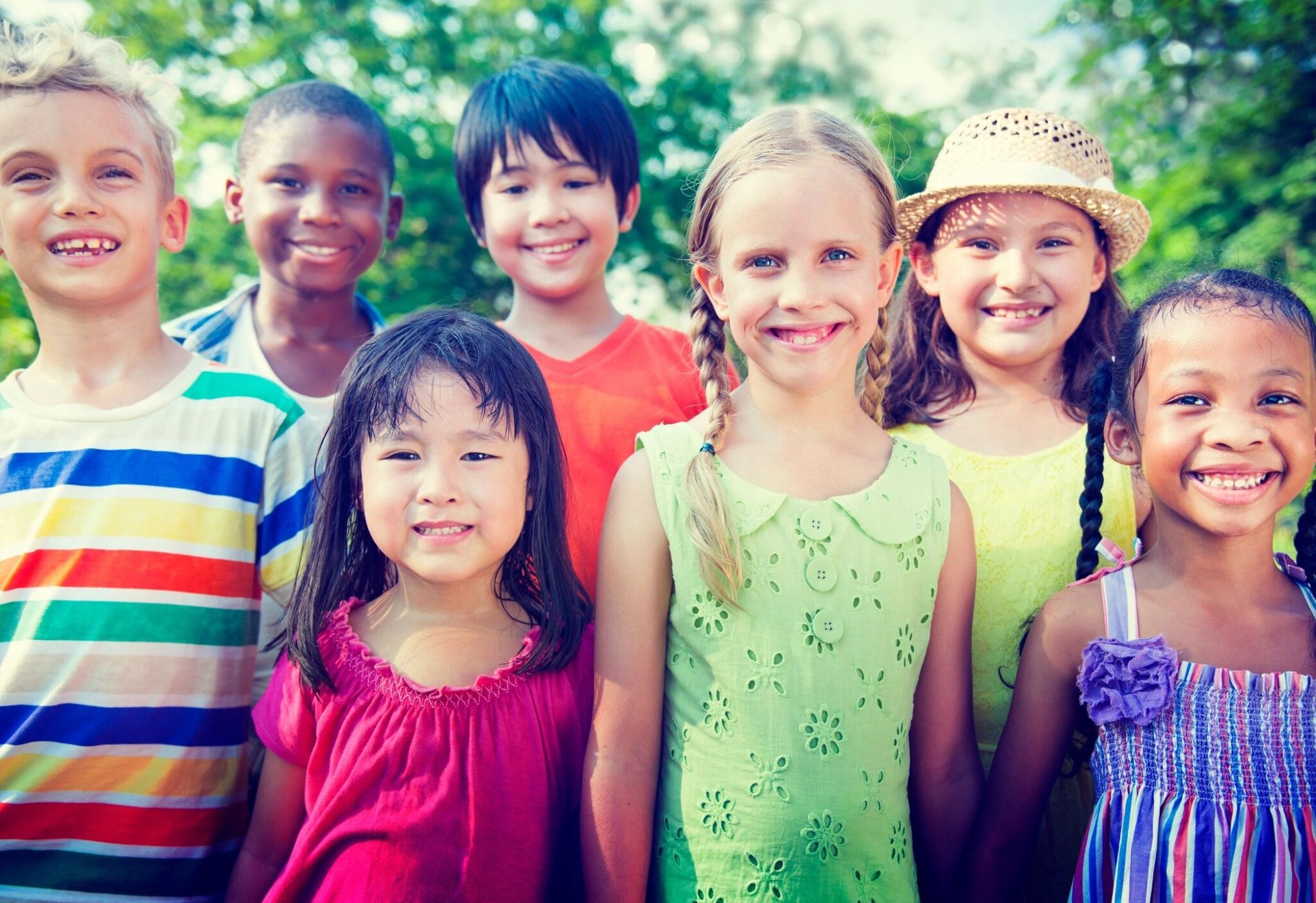 Smiling children standing together outdoors.